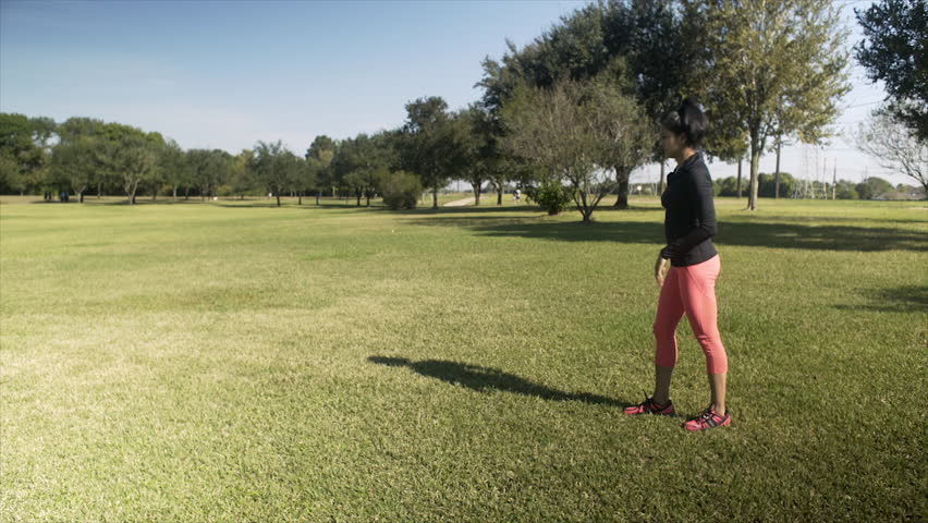 A women playfully does a cartwheel or round off on a bright sunny morning in the park