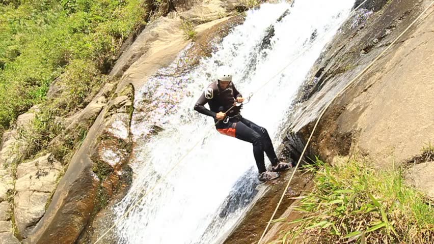 Powerful man descending a waterfall in Ecuadorian rain forest. Slow motion HD