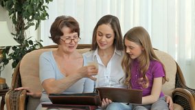 Grandmother and her granddaughters looking through family photo books and discussing photos