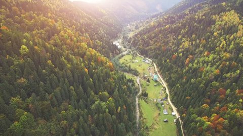Aerial Drone Footage View: Flight over autumn mountain village with forests, fields and river in sunrise soft light. Carpathian Mountains, Ukraine, Europe. Majestic landscape. Beauty world. 4K