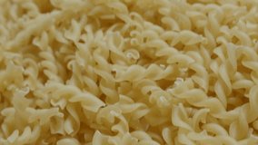 Corkscrew shaped pasta pile fall on table close-up 4K 2160p 30fps UltraHD footage -  Falling on top pieces of famous Italian food 3840X2160 UHD tilting video