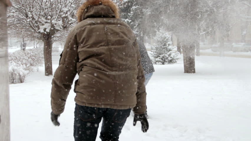 boy and girl play in snow  in winter, couple in love  throwing snowball 