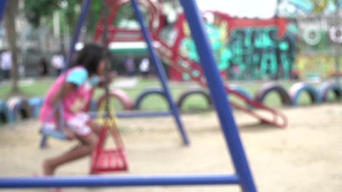 4K blur focus boy and little girl  swings swaying at playground