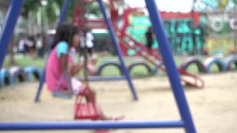 4K blur focus boy and little girl  swings swaying at playground