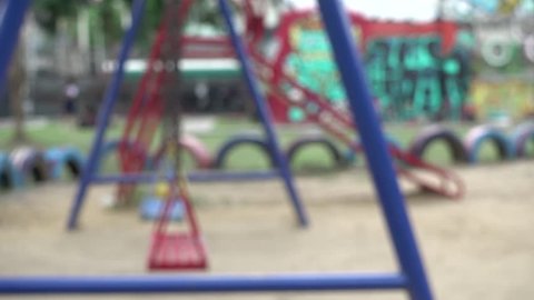 4K blur focus empty boy and little girl  swings swaying at playground