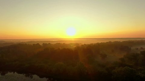 orange sunrise on the river, 4K aerial view of morning mist at sunrise, orange rays of the sun through the morning mist on the river,  Aerial view of mystical river at sunrise with fog