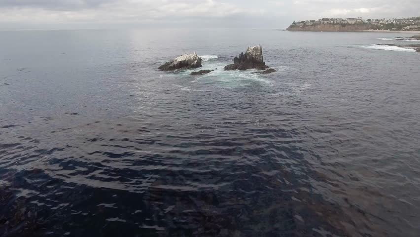 Waves crashing over rocks with birds on the rocks.  Rocks located just off shore from Crescent Bay in Laguna Beach, California.