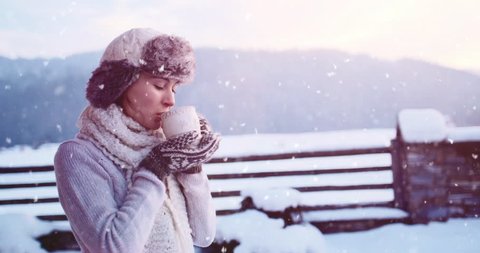 Woman drinking Hot Tea or Coffee from Festive Cup with Snowy Mountain View on Background. 4K SLOW MOTION 120fps. Beautiful Girl Enjoying Winter Morning or Evening Outdoors. Christmas Holidays