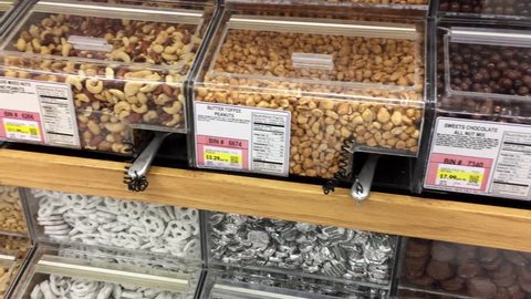 Bulk snacks available in grocery store. Various snacks include almonds, peanuts, pretzels, cashews.