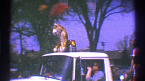 CLARENDON HILLS ILLINOIS 1969: a pickup truck with a light and a tiger sculpture on the roof, and a child in the back