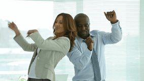 Two smiling businesspeople dancing cheerfully in office