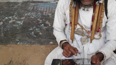 Man being helped and instructed to use a touch-screen tablet, Indian Rajasthani elderly male with big moustache wearing Traditional attire and ethic turban