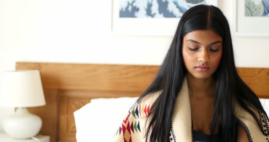 Woman using mobile phone in bedroom at home