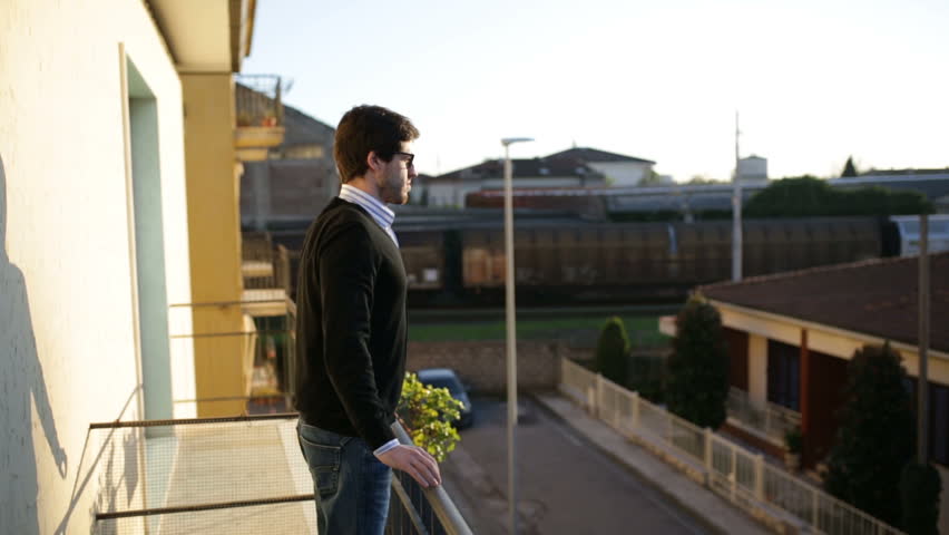 Boy standing up on his balcony is making some stretching