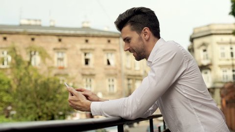 Handsome man browsing internet on smartphone and smiling to the camera
