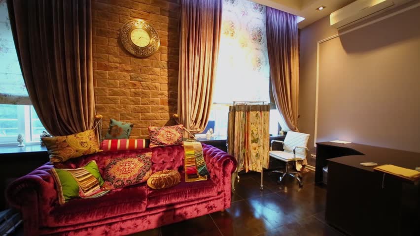 Panorama of shop interior with pillows on sofa and many cloth samples on shelves