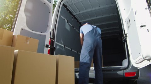 Delivery Man Loads Cardboard Boxes into his Van. Slow Motion. Shot on RED Cinema Camera in 4K (UHD).