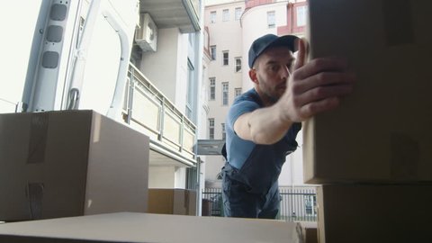 Warehouse Worker Unloads his Cargo Van onto the Sunny Street. In the Urban Area. Shot on RED Cinema Camera in 4K (UHD).