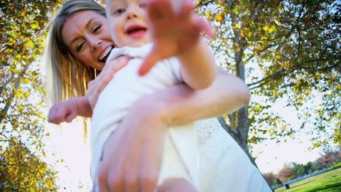 Blonde baby laughing as his beautiful young mom swings him through the air Stock Video
