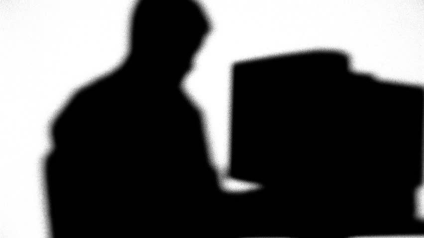 Silhouette of man typing on computer