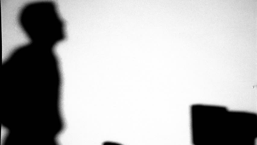 Silhouette of of man walking around desk