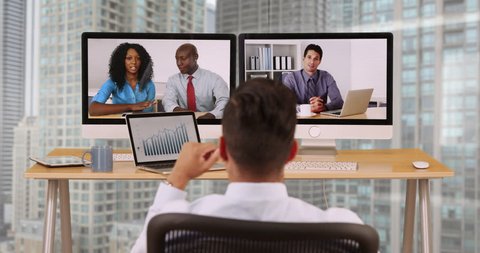 Hispanic business man in high rise corporate office having internet video conference with diverse group of coworkers. Businessman and international colleagues communicating over VoIP
