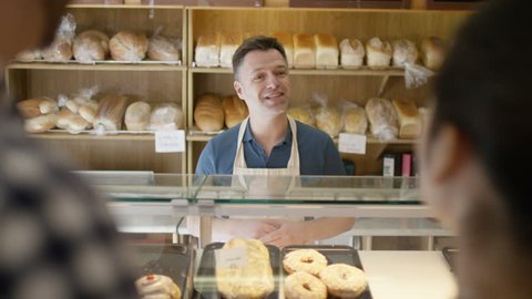 4K Couple in a bakery shop making contactless payment by cell phone (UK-Oct 2016)