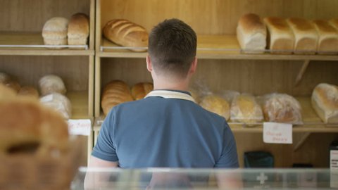 4K Friendly worker in bakery shop serving customer at the counter (UK-Oct 2016)