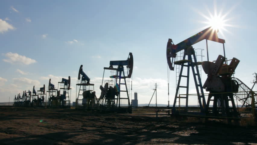 working oil pumps silhouette against sun
