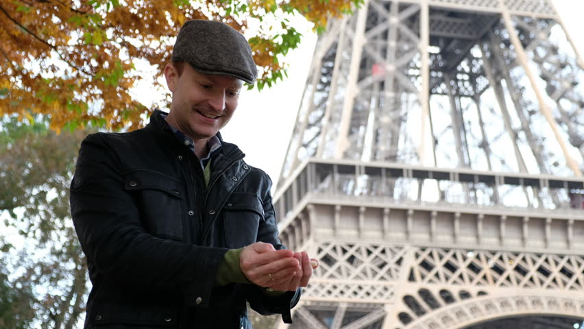 Tourist feeding pigeons with Eiffel tower in background 