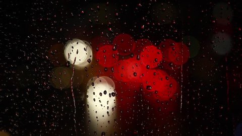 Rain drops on window with street bokeh lights, moving traffic bokeh lights