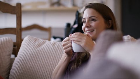 4K Attractive woman at home relaxing with a hot drink and tv