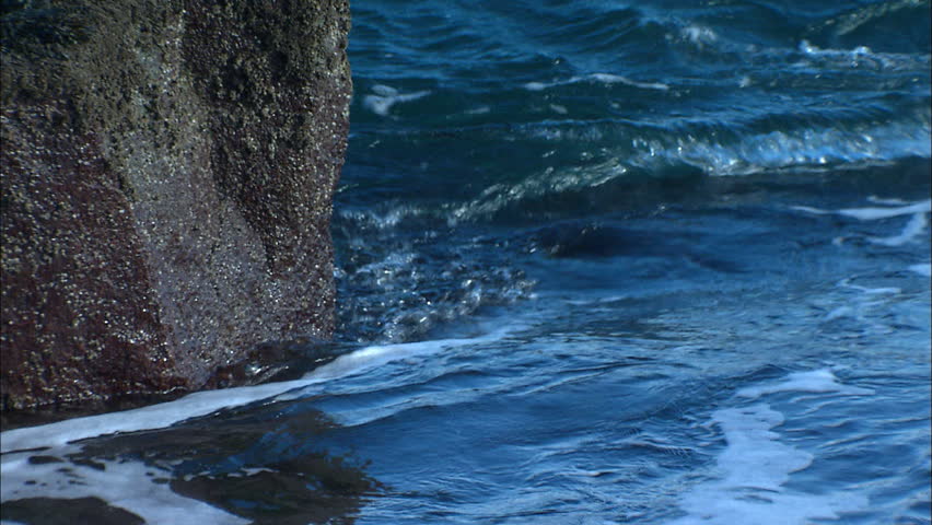 Closeup of waves crashing against rock wall