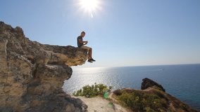 Researcher Man Climbs on a Rock. Large Tourist Backpack and Sports Odezhda.raduetsya Ascent to the Top. he Looks at the Sea From the Top. Video For Mativatsii