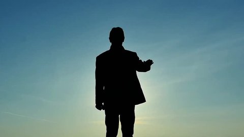 Mans silhouette dissolving on sunny sky background slow motion