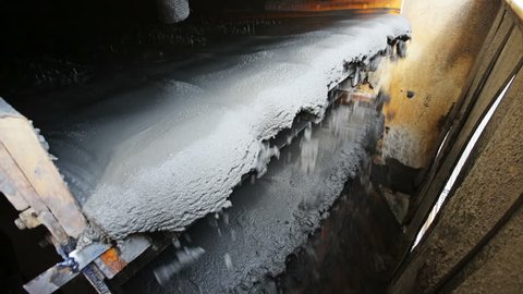 Raw concrete grout coming out of a concrete mixer on a conveyor