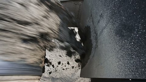 Raw concrete grout coming out of a concrete mixer on a conveyor
