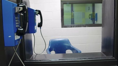 Meet area in prison jail where inmates talk on the phone with visitors behind plexiglass. Shot in 4K UHD.