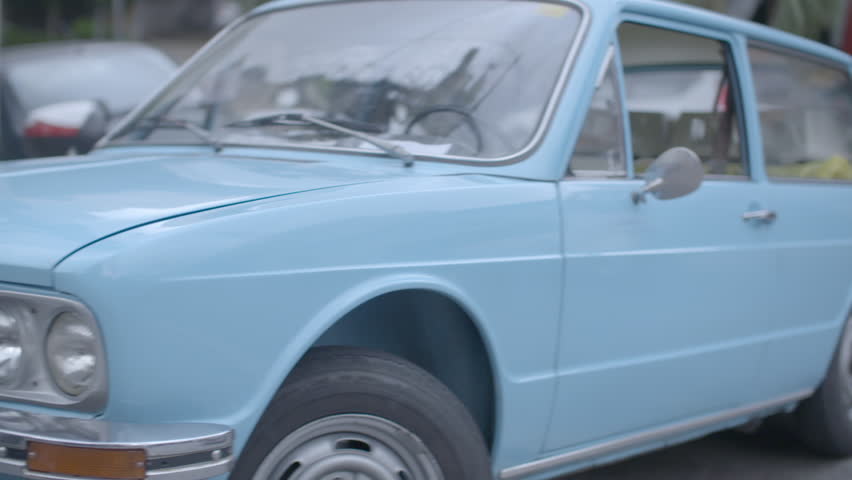 Old car with light blue painting parked on a street.