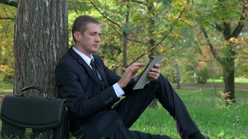 businessman sitting with a tablet in the park