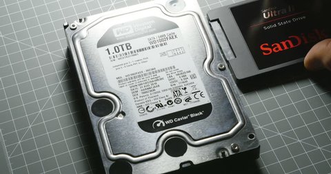 PARIS, FRANCE - CIRCA 2016: Man comparing HDD Hard Disk Drive with small SanDisk SSD Solid State Drive before computer upgrade