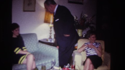 ROCKAWAY BEACH NEW YORK 1967: friend gathered meeting hugging each other sitting sofa smoking wearing coat dress lamp on side
