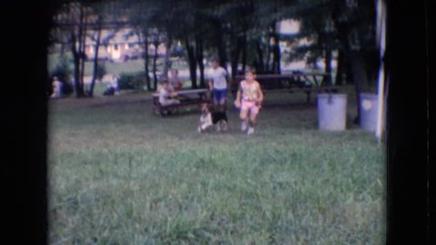 ATHENS OHIO 1966: children playing with basset hound in the yard.