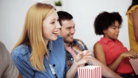 friendship, junk food, people and entertainment concept - happy friends eating popcorn, watching tv and laughing at home