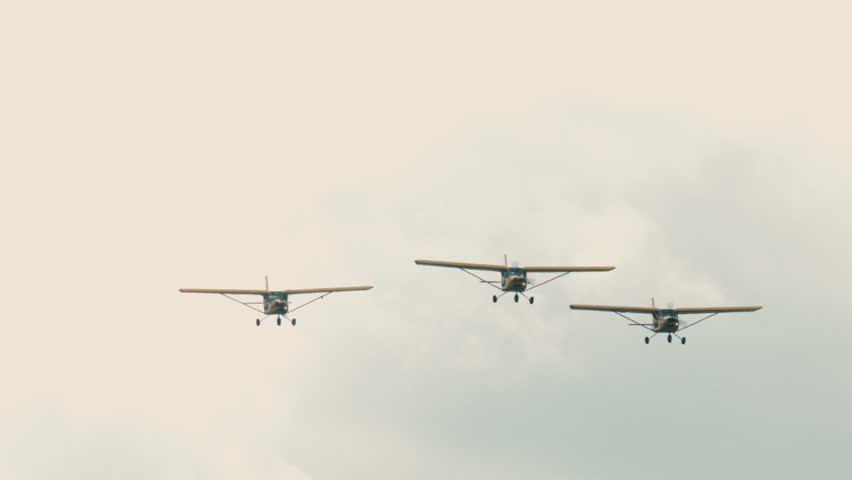 Three small single engine airplanes doing stunts