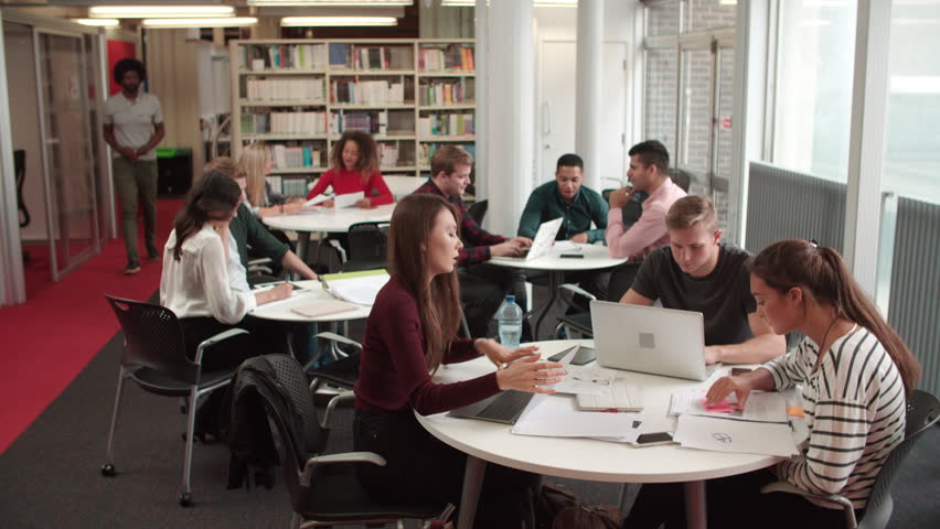 Busy University Library With Students And Tutor