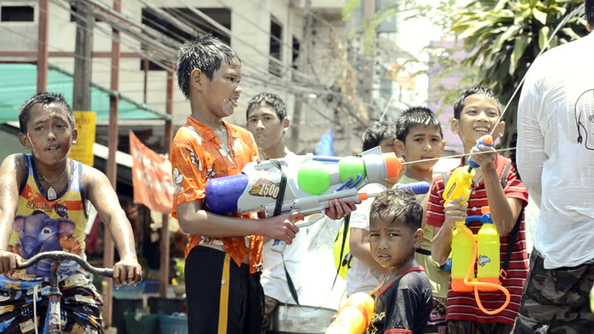 BANGKOK - APRIL 13: Young boy with a water pistol spraying people and cars