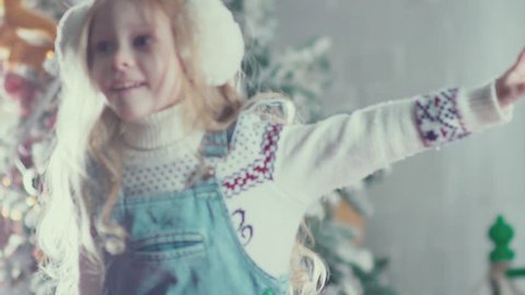 Slow motion. A cute little girl with long blond hair jumping and spinning, enjoying Christmas. Holiday in childhood. Girl like a little angel. Jumping on the bed. Children's pranks