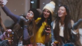 Group of happy female friends drink mulled wine and taking selfie with a smartphone in the outdoor cafe in winter. 60 FPS slow motion, 4K UHD RAW edited footage