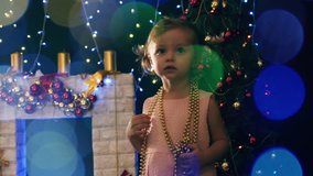Toddler girl, background of decorated Christmas tree, blurred garlands light